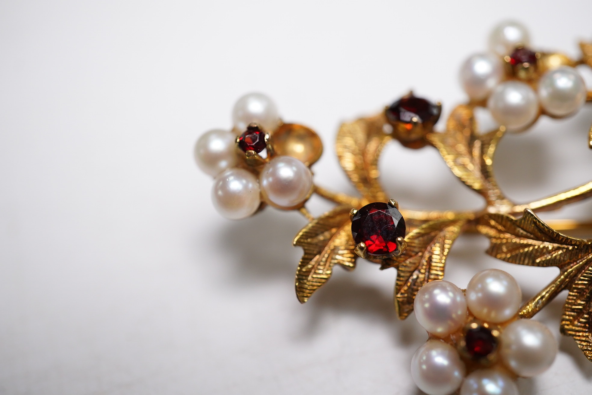 A 1960's 9ct gold, cultured pearl and garnet cluster set foliate spray brooch, 52mm (three pearls missing), gross weight 9.3 grams. Condition - poor